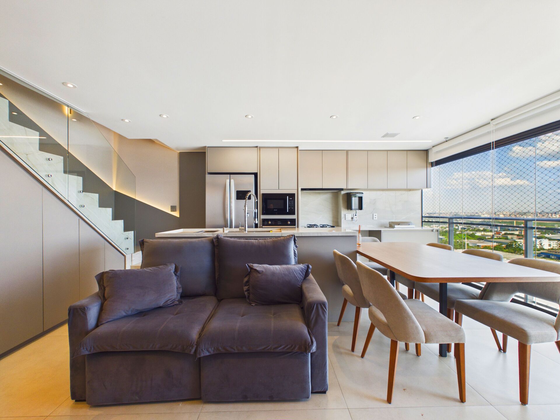 Sala, cozinha e jantar integrados, com escada para o andar superior