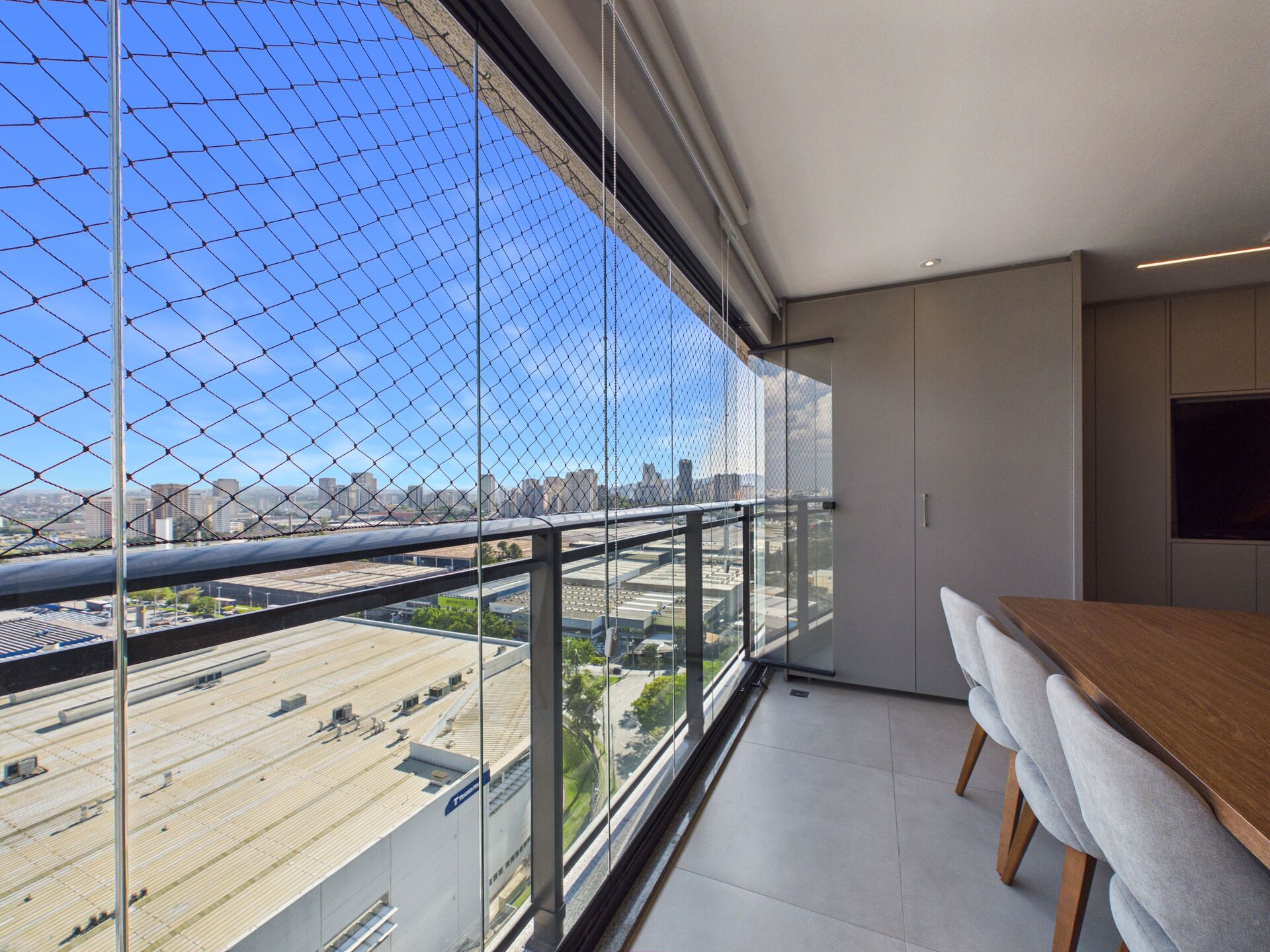 Varanda envidraçada com mesa de jantar e vista da cidade